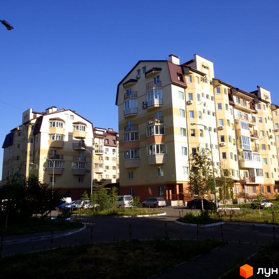 Житловий комплекс вул. Дяченка з сучасними фасадами та прибудинковою територією, де розташовані автомобілі та зелена зона.