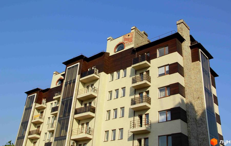 Зовнішній вигляд житлового комплексу Premium Residence із балконами та вікнами на тлі блакитного неба. Будинок має багатоповерхову структуру з елементами оздоблення з дерева та каменю.