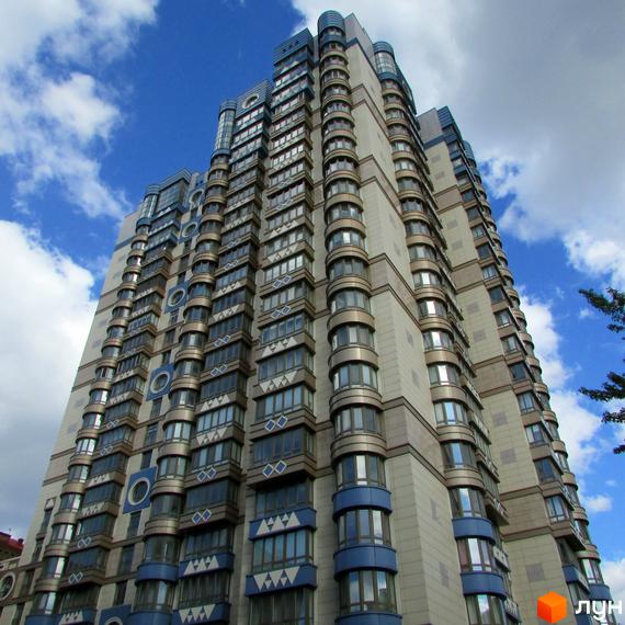 Житловий комплекс Липська вежа з високими фасадами та великими вікнами. Прибудинкова територія озеленена та облаштована для відпочинку.