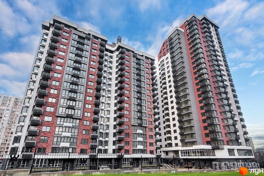 Високі будинки житлового комплексу West House з фасадами у світлих тонах. Біля будинків зелена трава та блакитне небо.