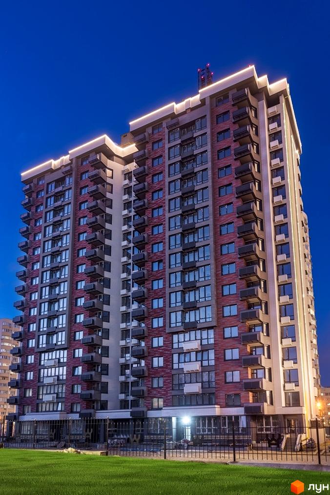 Висотна новобудова ЖК West House з фасадом з червоної цегли. На передньому плані газон та кована огорожа.