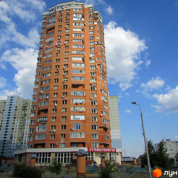 Висотна цегляна новобудова з численними вікнами та кондиціонерами. На першому поверсі розташована вивіска 