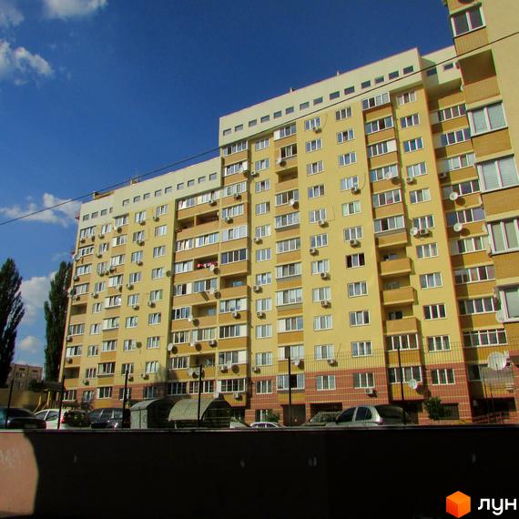 Житловий комплекс на вул. Васильченка, 3/24 – висотна жовта будівля з багатьма вікнами та кондиціонерами. Біля будинку розташовані автомобілі та паркан.