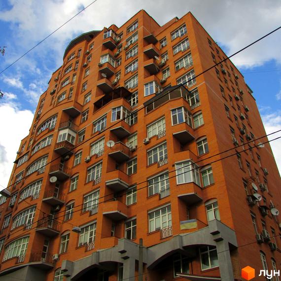Житловий комплекс на вул. Дмитрівська, 66а, з червоною цегляною фасадою та балконами. Прибудинкова територія з зеленими насадженнями.
