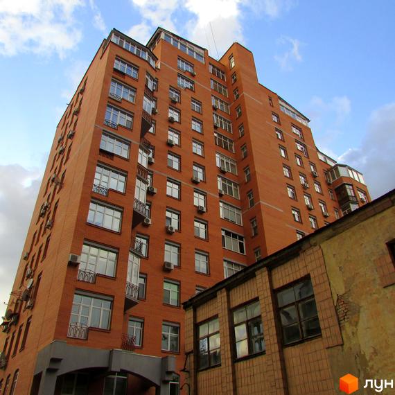 Житловий комплекс на вул. Дмитрівська, 66а, з червоної цегли та великими вікнами. Прибудинкова територія з сусідніми будівлями.