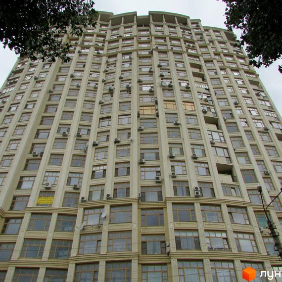 Високий житловий комплекс Golden Park з бежевим фасадом та численними вікнами. Навколо будинку видно зелені дерева.