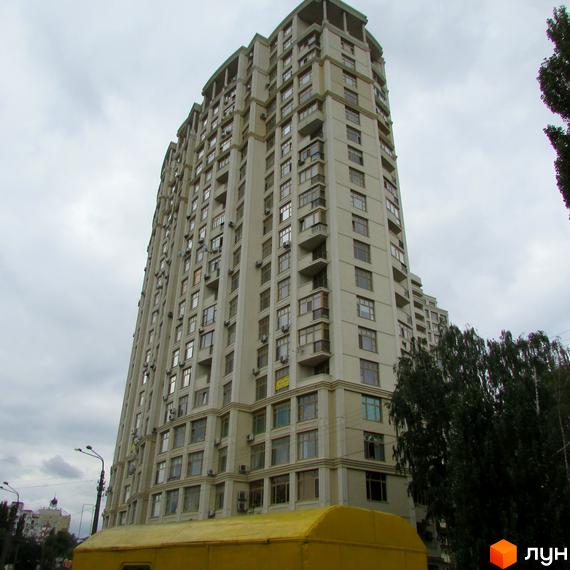 Багатоповерховий житловий будинок Житловий комплекс Golden Park світлого кольору з численними вікнами та балконами. Поруч жовтий транспортний засіб та зелені дерева.