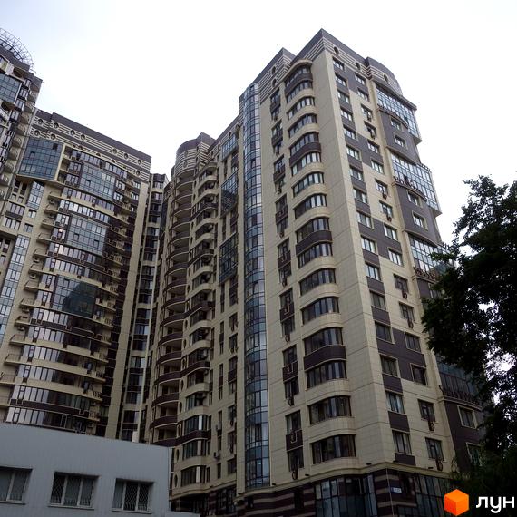 Багатоповерховий будинок Житлового комплексу Престиж Холл з фасадом світлого та темного кольорів, великими вікнами та балконами. Поруч розташоване дерево.