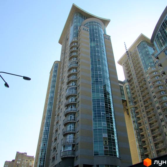 Високий будинок Житлового комплексу Тріумф з вигнутим скляним фасадом та численними балконами. Фасад будівлі має горизонтальні смуги.