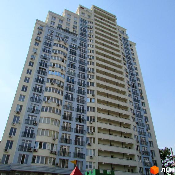 Житловий комплекс на вул. Крамського, 9, з фасадом з балконами та великими вікнами. Прибудинкова територія з дитячими майданчиками.