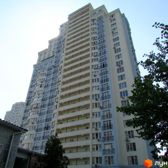 Житловий комплекс на вул. Крамського, 9, з великими балконами та сучасними вікнами, оточений зеленими насадженнями.