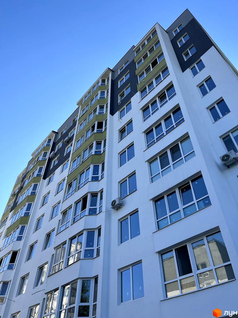 Висотна новобудова з білими фасадами та великими вікнами. Верхня частина будівлі пофарбована у темний колір, що контрастує з білим.