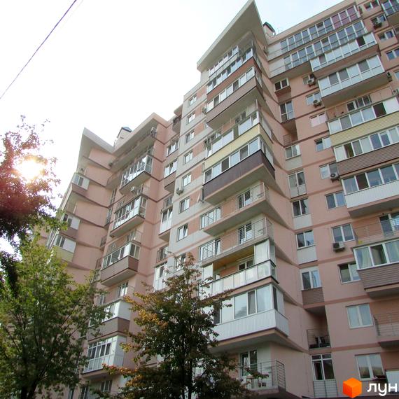 Житловий комплекс на вул. Януша Корчака, 25. Вид на фасад будинку з балконами та прибудинковою територією з зеленими насадженнями.