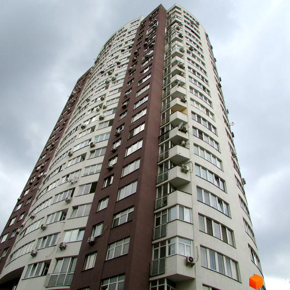 Житловий комплекс Вертикаль з сучасним фасадом та балконами, прибудинкова територія з зеленими насадженнями.