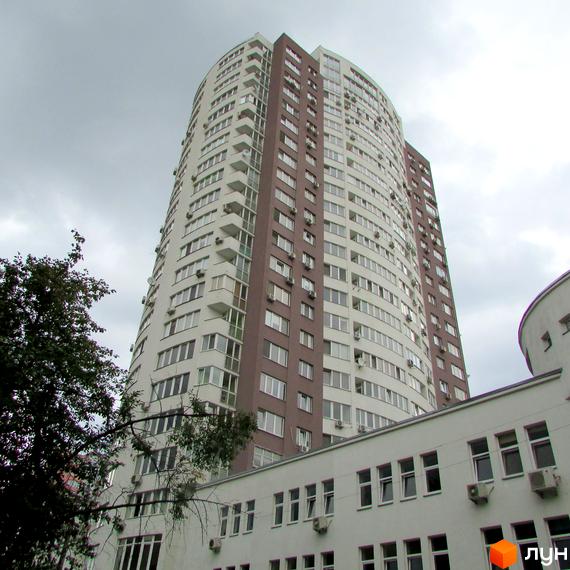 Житловий комплекс Вертикаль з висотним будинком та прибудинковою територією, оточений зеленими насадженнями.