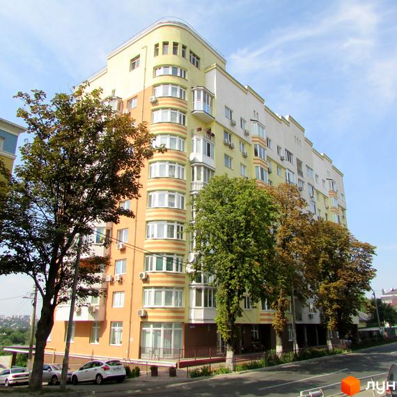 Житловий комплекс на вул. Козацька, 112-114 з сучасною архітектурою та зеленими насадженнями навколо. Прибудинкова територія облаштована для комфортного проживання.