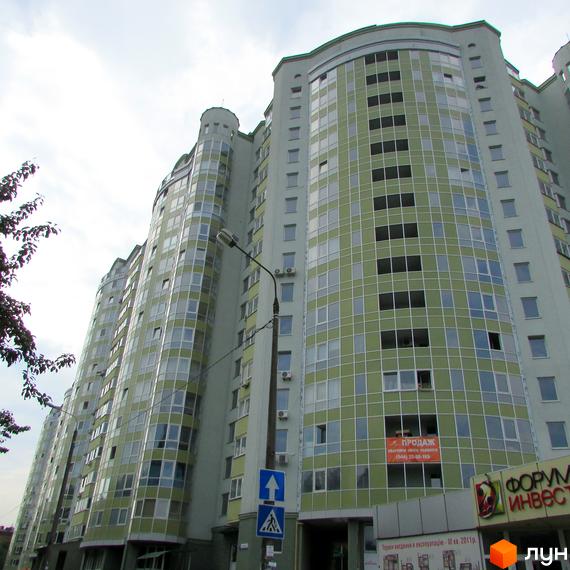 Житловий комплекс Васильківський з сучасною фасадною обробкою та великою кількістю вікон. Прибудинкова територія з зеленими насадженнями та зручними пішохідними доріжками.