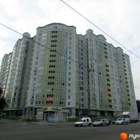 Житловий комплекс Васильківський з сучасною архітектурою та великими вікнами, прибудинкова територія з автомобілями та пішоходами.