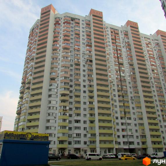 Житловий комплекс на вул. Драгоманова, 6/1, з сучасним фасадом та прибудинковою територією, де розташовані автомобілі.