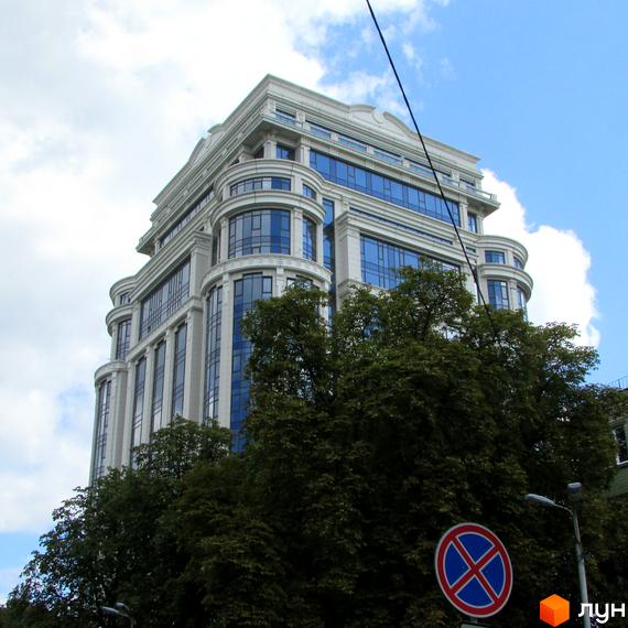 Вид на житловий комплекс Diamond Hill з великою кількістю вікон та зеленою територією навколо. Будинок оточений деревами та зупинкою для автомобілів.