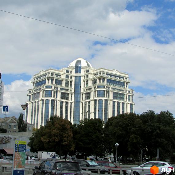 Житловий комплекс Diamond Hill з сучасним фасадом та великими вікнами, оточений зеленими насадженнями та автомобілями на прибудинковій території.