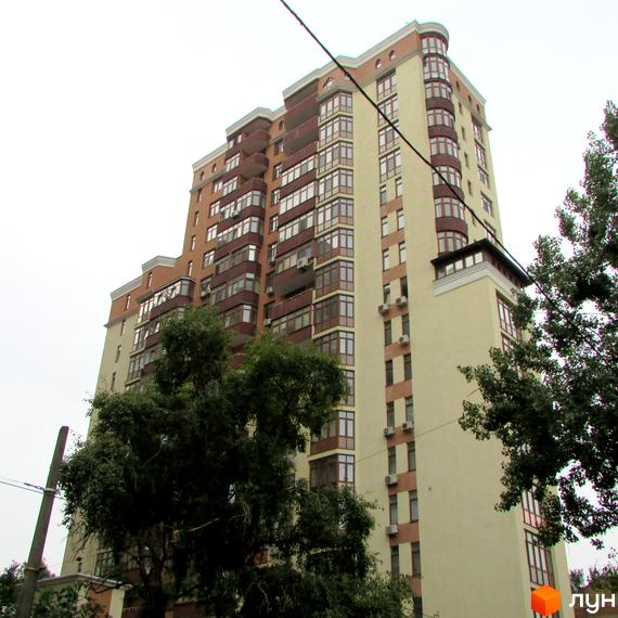 Багатоповерховий житловий комплекс на вул. Коперника, 11. Будинок має світло-бежевий фасад з коричневими елементами та численними заскленими балконами. Навколо видно зелені дерева.