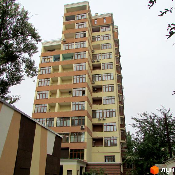 Житловий комплекс на вул. Коперника, 11. Багатоповерховий будинок світло-бежевого та коричневого кольору з численними вікнами та балконами. Навколо будинку зелені дерева та кущі.