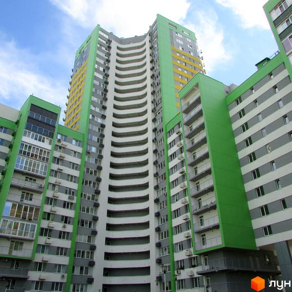 Багатоповерховий будинок Житлового комплексу Паркове місто з вигнутим фасадом, пофарбований у зелені, сірі та білі кольори, з численними вікнами та балконами.