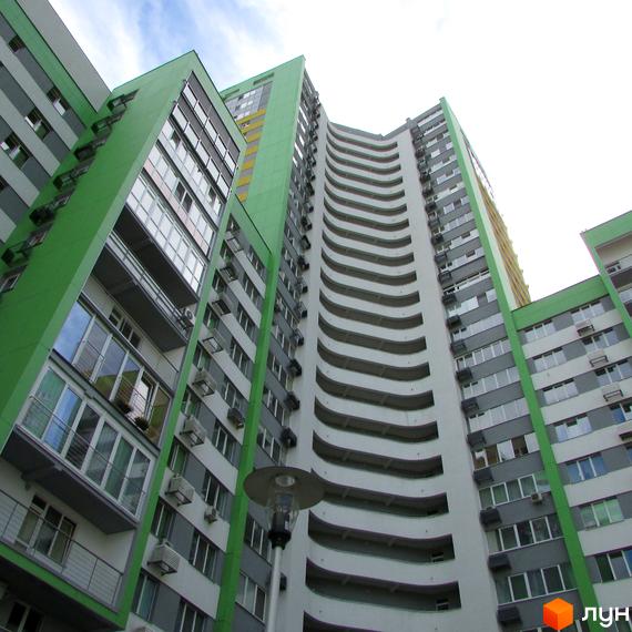 Фасад житлового комплексу Паркове місто з зеленими та сірими панелями, великими вікнами та вигнутими балконами.