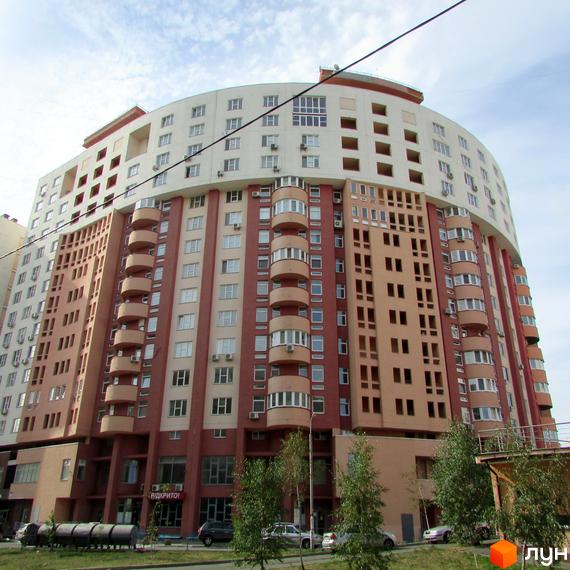 Житловий комплекс Перлина Кадетського Гаю з фасадом у світлих тонах та балконами. Прибудинкова територія з зеленими насадженнями.