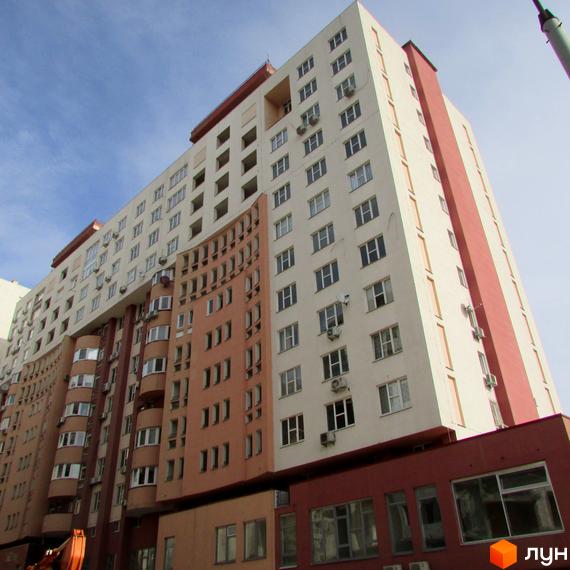 Житловий комплекс Перлина Кадетського Гаю: висока будівля бежевого та теракотового кольорів з вигнутим фасадом та численними вікнами.