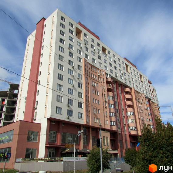 Житловий комплекс Перлина Кадетського Гаю: багатоповерховий будинок з біло-рожевим фасадом, балконами та комерційними приміщеннями на перших поверхах.