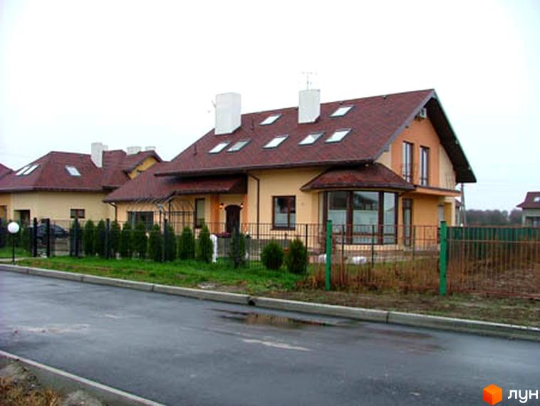 Будинки в Котеджному містечку Петрушки з коричневою черепицею та світлими стінами. На території є зелені насадження та огорожа.