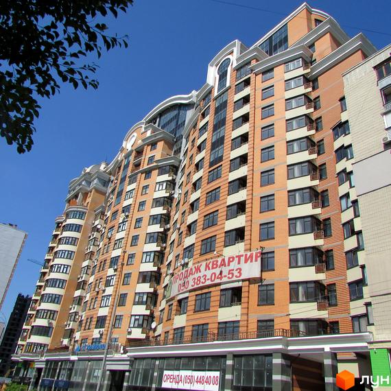 Житловий комплекс на бул. Лесі Українки, 7б, з фасадом з червоної цегли та великими вікнами, прибудинкова територія з озелененням.