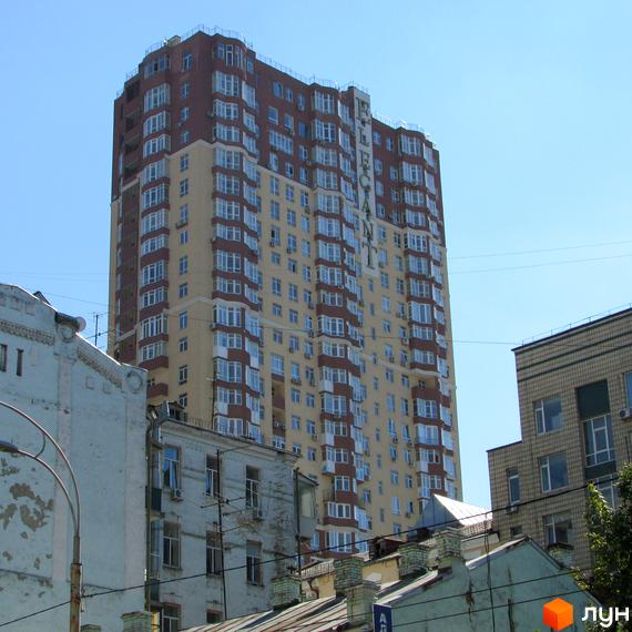 Житловий комплекс Елегант висотою 18 поверхів з балконами. Прибудинкова територія з невеликими будівлями та зеленими насадженнями.