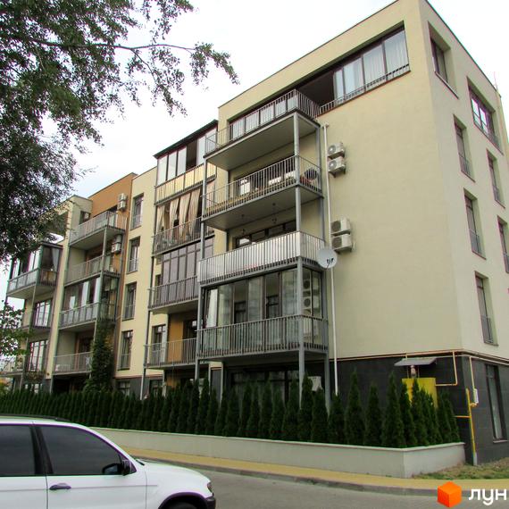 Житловий комплекс Ліпінка з балконами та великими вікнами, озеленена прибудинкова територія з хвойними рослинами.