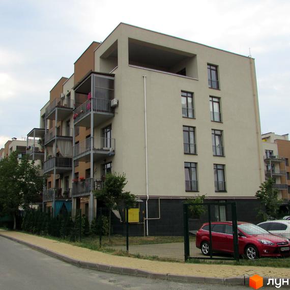 Будинок житлового комплексу ЖК Ліпінка з балконами та вікнами. На прибудинковій території видно паркан та автомобілі.