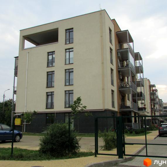 Житловий комплекс Ліпінка: багатоповерховий будинок світло-бежевого кольору з балконами та вікнами, огороджена територія з деревами та автомобілем.