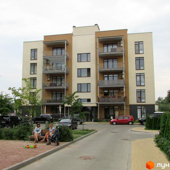 Житловий комплекс Ліпінка. Фасад будинку з балконами та кондиціонерами. Прибудинкова територія з лавками та автомобілями.