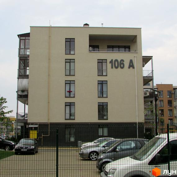 Житловий комплекс Ліпінка, фасад будинку №106 А з вікнами та балконами. На прибудинковій території розташовані припарковані автомобілі та огорожа.