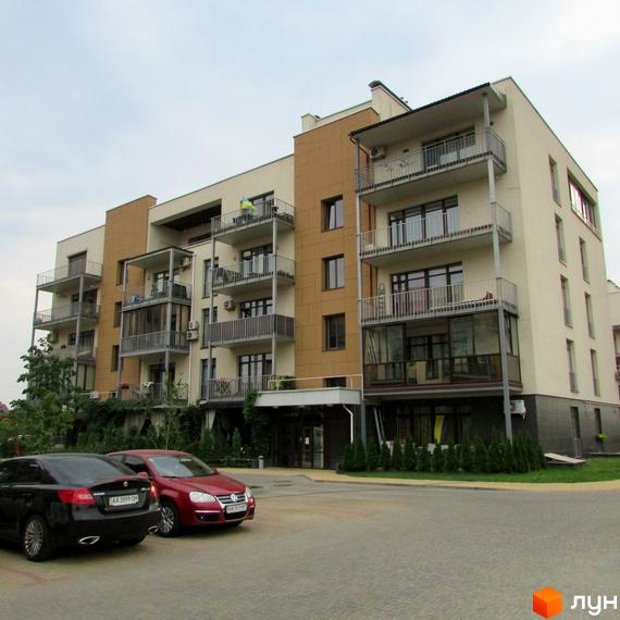 Зовнішній вигляд будинку житлового комплексу Ліпінка з балконами та вікнами. Прибудинкова територія з автомобілями та зеленими насадженнями.