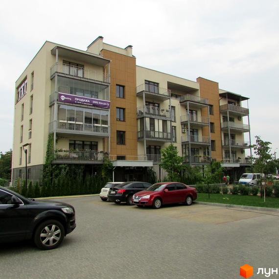 Житловий комплекс Ліпінка – фасади будівель з балконами та парковка з автомобілями. На фасаді розміщено банер 