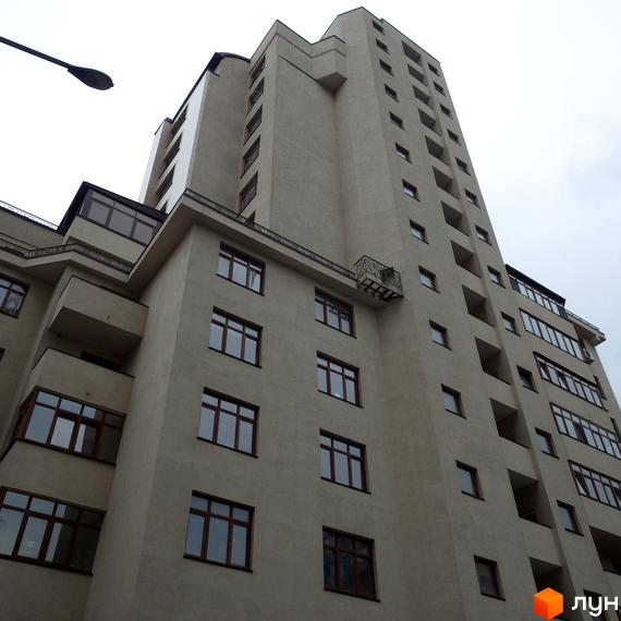 Житловий комплекс на вул. Антоновича, 103, з фасадом та великими вікнами. Прибудинкова територія з зеленими насадженнями.