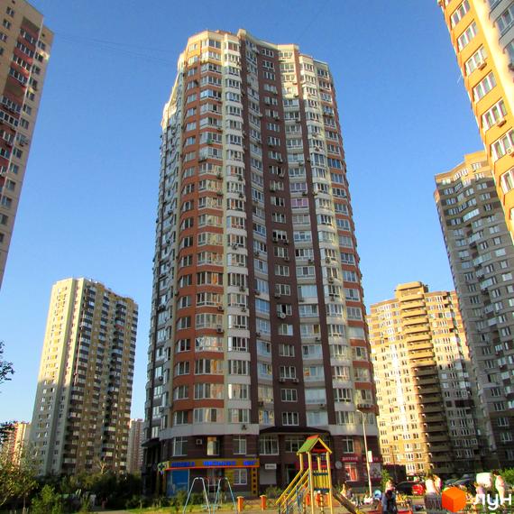 Житловий комплекс вул. Ахматової, 34, з висотними будинками та прибудинковою територією з дитячим майданчиком.