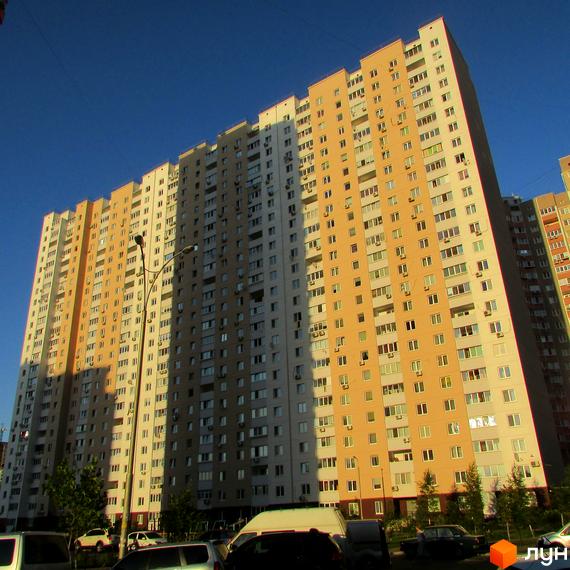 Вид на багатоповерховий житловий комплекс на вулиці Урлівській, 38а, з фасадами світло-бежевого та сірого кольорів. Навколо комплексу видно дерева та припарковані автомобілі.