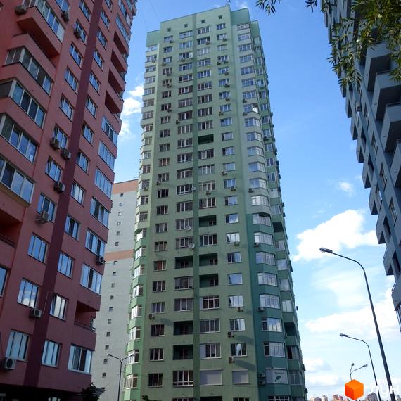 Високий житловий комплекс на вул. Феодосійська, 2, світло-зеленого кольору з численними вікнами та балконами. Поруч видно інші багатоповерхові будинки.