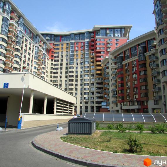 Житловий комплекс Сонячна брама: багатоповерхові будинки з різнокольоровими фасадами та балконами. На території є в'їзд до паркінгу та зелені насадження.