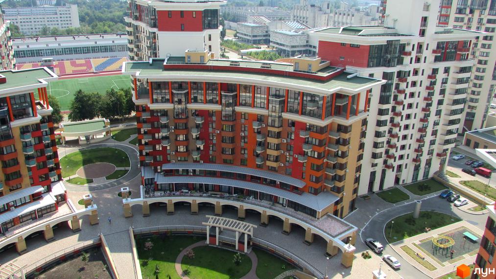 Житловий комплекс Сонячна брама: багатоповерхові будинки з кольоровими фасадами та балконами. Прибудинкова територія має зелені зони, доріжки та стадіон.