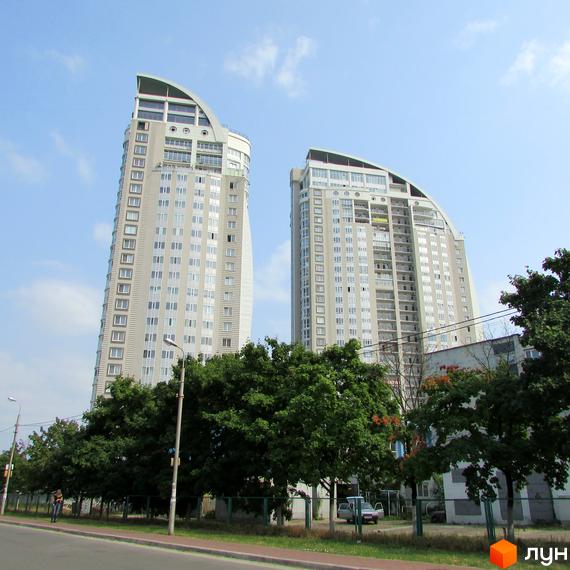 Зображення житлового комплексу на просп. Володимира Івасюка, 2: два високі будинки зі світлими фасадами та вигнутими дахами, оточені зеленими деревами.