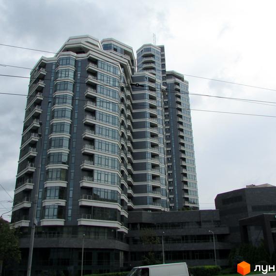 Житловий комплекс PecherSKY з сучасною архітектурою та великими вікнами. Прибудинкова територія озеленена та облаштована для відпочинку.